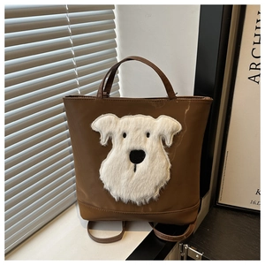 Detail of a brown tote bag with a white plush schnauzer dog patch and shoulder straps