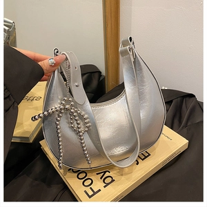 Close-up of metallic silver crescent hobo bag with fashion text and bead bow charm