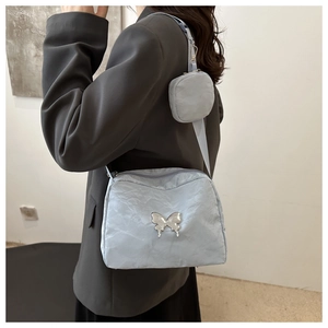 Detail of grey-blue crossbody bag with silver butterfly charm and small round pouch