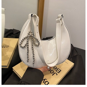 Detail of white crescent bag with silver beaded bow charm and embossed branding