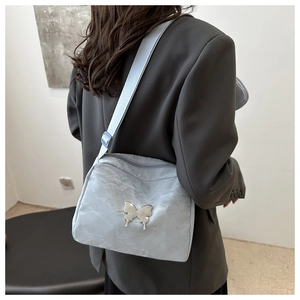 Close-up of a light blue pleated crossbody bag featuring a silver metal butterfly buckle