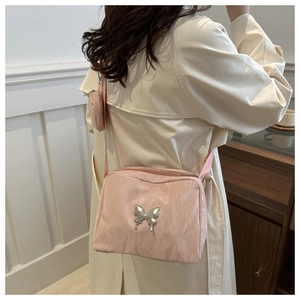 Detail of pink nylon crossbody bag with butterfly ornament and round coin purse on model