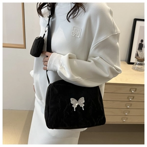 Detail of black crossbody bag with silver butterfly charm and detachable mini pouch