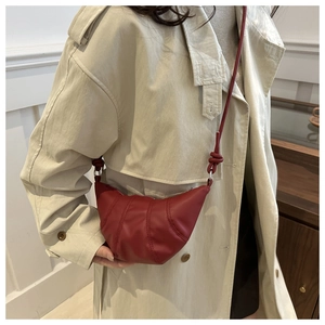 Detail of dark red croissant crossbody bag with quilted panels and knotted shoulder strap