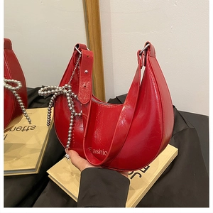 Detail of red patent leather crescent bag with decorative silver bead chain