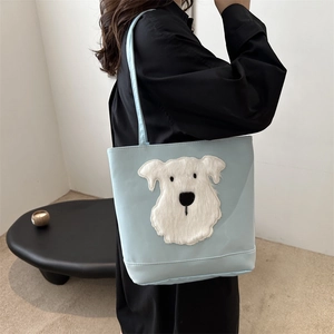 Light blue canvas tote bag with cute cartoon dog embroidery worn by a model in black