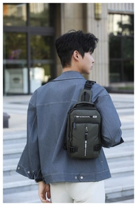 Outdoor shot of a man wearing a dark green nylon chest bag with layered zipper pockets