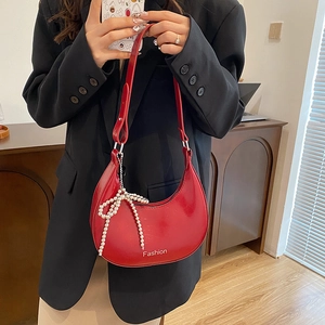 Red crescent moon shoulder bag with glossy finish and pearl bow charm shown with model