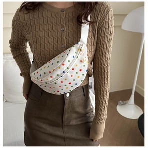 Detailed view of white polka dot waist bag featuring a metal letter A zipper pendant