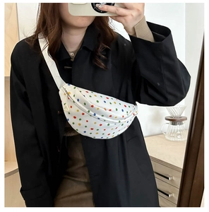 Close-up of a white canvas waist bag with colorful polka dots and an adjustable strap