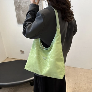 Fashionable mint green ruched tote bag with triangle logo, shown on a model in gray suit