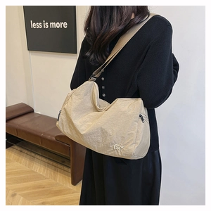 Detailed view of beige crossbody bag with textured fabric and wide strap on model
