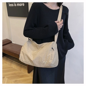 Detailed shot of beige nylon crossbody bag featuring silver logo and wide shoulder strap
