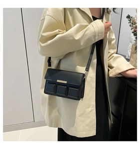Detail of black crossbody bag with 3D textured blocks and gold metal bar accent
