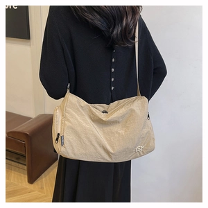 Detail of beige wrinkled nylon crossbody bag with fashion label and metal logo
