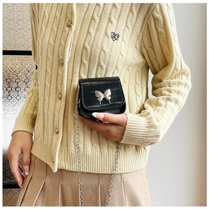 Detail of a mini black crocodile texture crossbody bag with silver butterfly metal clasp