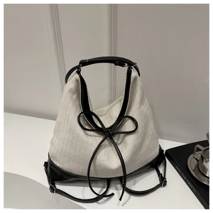 Close-up of canvas and leather patchwork tote with bow detail and contrast stitching