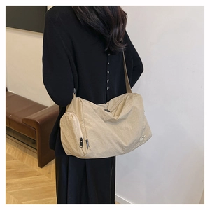Detail view of a beige minimalist large capacity crossbody bag with side zipper and strap