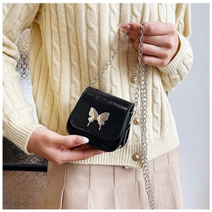 Close-up of black leather mini chain bag with silver butterfly buckle detail