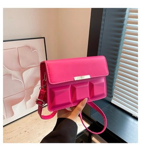 Detail of rose red square bag with chocolate texture and gold metal buckle