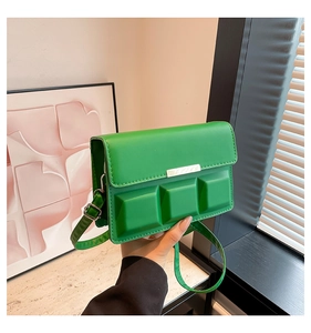 Detail of green crossbody bag featuring three 3D square patterns and gold metal clasp