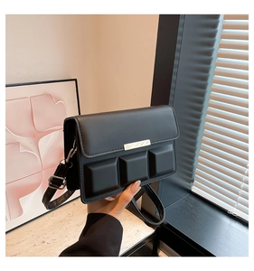 Detail of black rectangular crossbody bag with 3-grid geometric texture and gold buckle