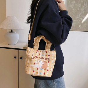 Cute yellow canvas bucket bag with cartoon cat print and adjustable strap shown on model