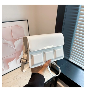 Detail of white crossbody bag featuring unique 3D geometric embossed texture and silver hardware