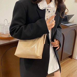 Minimalist beige glossy leather crescent underarm bag shown from a side profile view