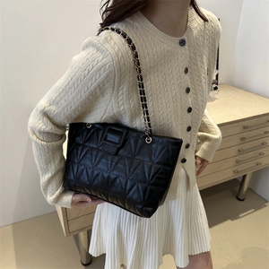 Borsa a spalla trapuntata con catena mostrata su una modella in un interno accogliente