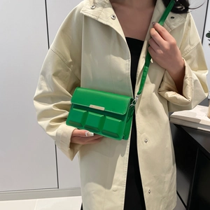Minimalist green faux leather square crossbody bag worn with a beige trench coat