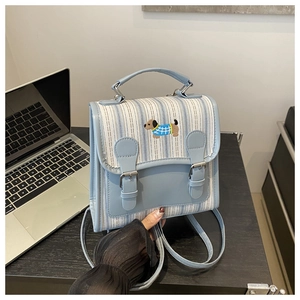 Close-up of small blue striped backpack with embroidered dachshund and buckle straps