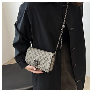 Detail of vintage square crossbody bag with clover pattern and metallic clasp on model