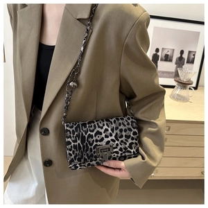 Detailed view of leopard print crossbody bag with metallic chain strap and turn-lock