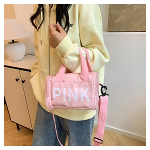 Sac cylindrique rose avec logo PINK blanc, bandoulière réglable et poignée en sangle