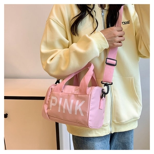 Détail du sac de sport cylindrique rose avec logo PINK blanc et bandoulière