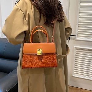Vintage orange leather crossbody bag with crocodile texture and gold clasp on model