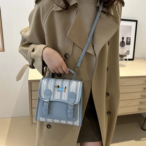 Chic blue and white striped crossbody bag with cute dog patch shown on a model