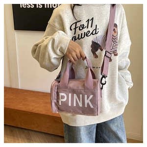 Détail d'un sac de sport rose cylindrique avec lettres PINK et bandoulière violette