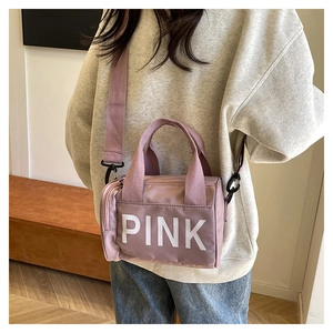 Sac bandoulière de sport en nylon rose avec lettrage PINK porté par un mannequin