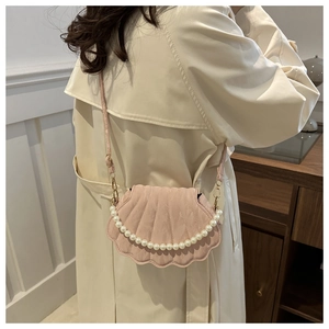 Detail of light pink shell-shaped crossbody bag with pearl handle and quilted texture