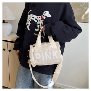 Détail du sac cylindrique en toile crème avec lettrage PINK et bandoulière réglable