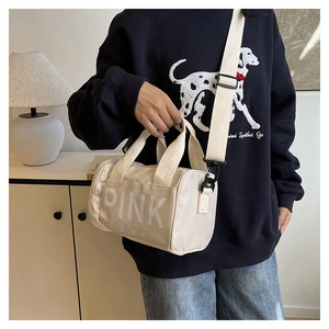 Détail d'un sac de sport cylindrique beige avec logo PINK blanc et bandoulière