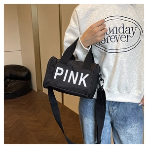 Vue latérale du sac polochon en toile noire avec logo PINK et bandoulière réglable