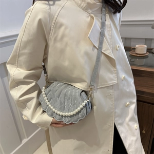 Chic grey shell-shaped crossbody bag with pearl strap and pleated texture on a model