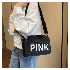 Détail d'un sac de sport cylindrique noir avec logo PINK blanc et bandoulière large