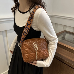 Brown quilted crossbody bag with golden S-buckle, fringe tassel and wide textile strap