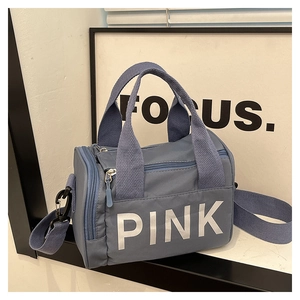 Détail du sac polochon en nylon bleu avec lettrage PINK blanc et poignées robustes