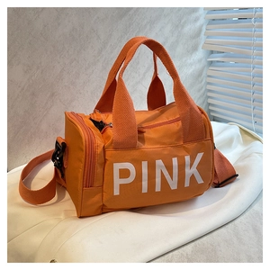 Gros plan du sac de sport orange cylindrique en nylon avec logo PINK blanc et sangle