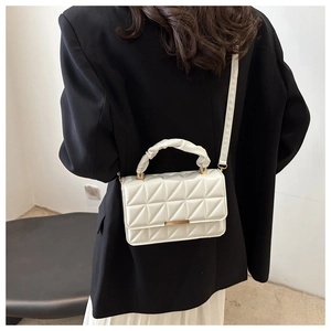 Detail view of white quilted square bag with gold hardware and ruched top handle